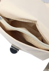 Sac en tissu beige à texture lisse, doté d'une fermeture argentée et de deux compartiments intérieurs zippés avec une doublure à motifs.