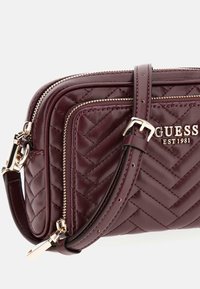 Borsa a tracolla in pelle trapuntata color bordeaux con hardware dorato, due scomparti con zip e tracolla regolabile. Logo impresso sul fronte.