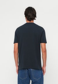 Black cotton t-shirt with a classic crew neck, short sleeves, and a straight hem, paired with blue denim jeans. No visible patterns or graphics.