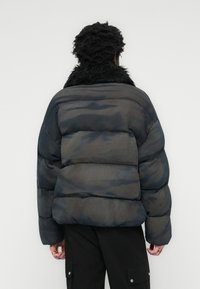Black and gray puffer jacket with a quilted design, featuring a faux fur collar and a slightly glossy finish.