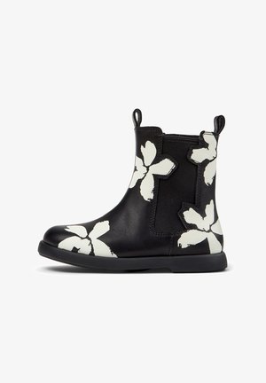 Botim preto até ao tornozelo com padrões florais brancos, painel lateral elástico, alças de puxar na frente e atrás, e sola plana.