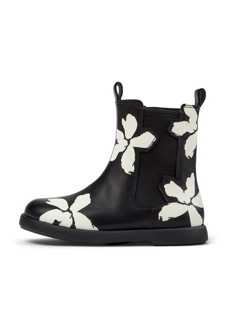Bottine noire avec des motifs floraux blancs, panneau latéral élastique, languettes à l'avant et à l'arrière, et semelle plate.