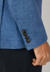 Manica di blazer in lino blu, con quattro bottoni scuri e dettagli cuciti. Tessuto liscio con una vestibilità su misura.