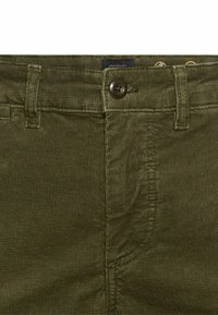 Olijfgroene corduroy broek met een gestructureerd oppervlak, voorzien van een knoopsluiting aan de voorkant en standaard riemlussen.