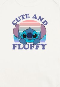 Bílá tkanina s grafikou modré kreslené postavy s velkýma ušima a očima, text nahoře zní "CUTE AND" a dole "FLUFFY" v purpurové barvě.