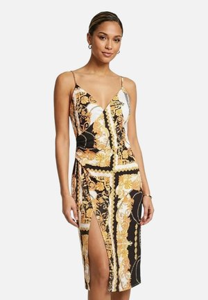 Donna che indossa un vestito midi senza maniche con disegni barocchi dorati e neri e uno spacco alto su un lato.