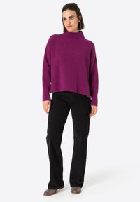Purple ribbed knit sweater with a high neckline, paired with black corduroy pants and gray ankle boots. Simple, relaxed fit with dropped shoulders.