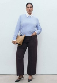 Light blue sweater with white collar, dark brown wide-leg pants, and a tan clutch bag. Black pointed shoes. Smooth fabric textures.
