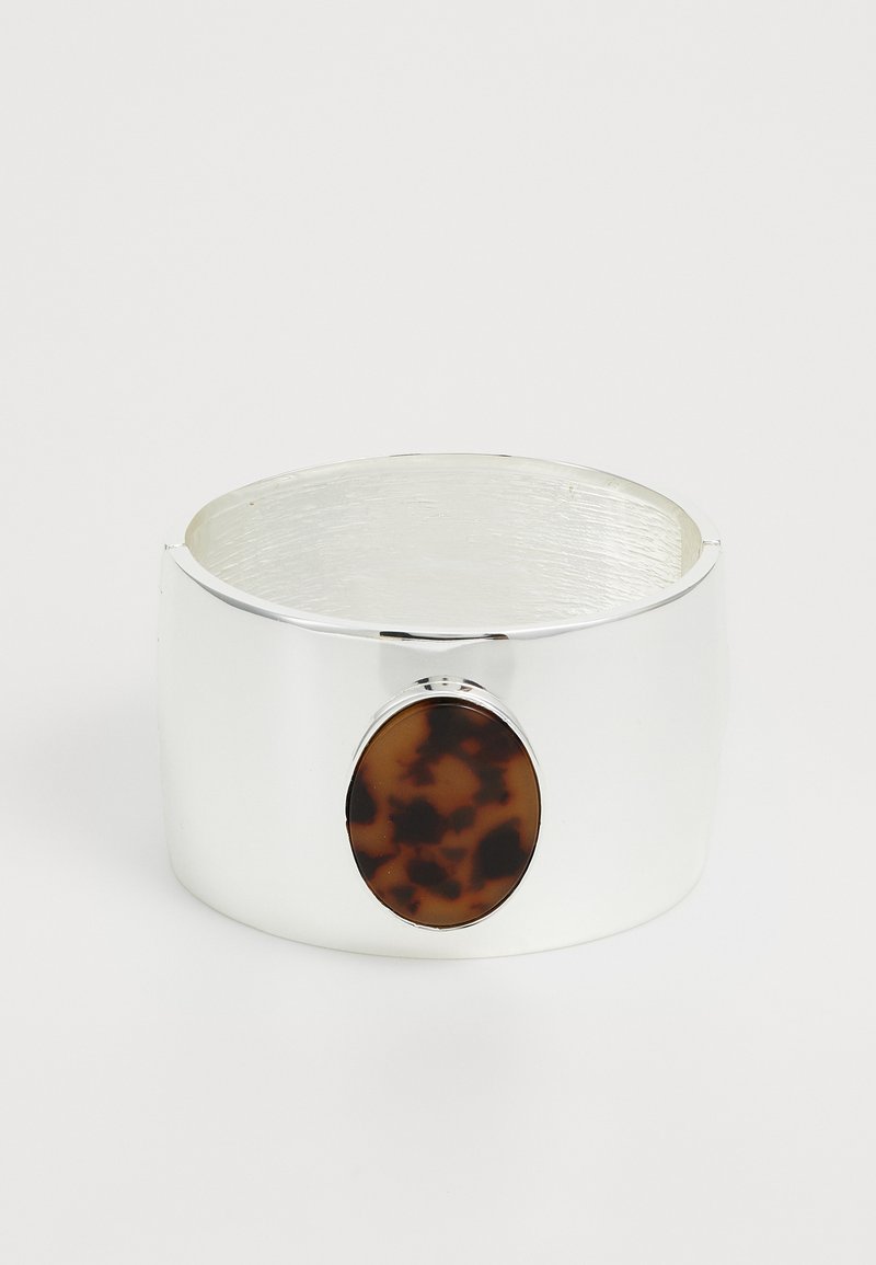 Bracciale in argento con finitura lucida, caratterizzato da un accento in tartaruga marrone in una forma ovale. Texture liscia simile al legno.