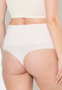 Hochtaillierte weiße Unterwäsche aus einem glatten, dehnbaren Stoff. Verfügt über ein nahtloses Design und durchsichtige Einsätze für Komfort und Passform.