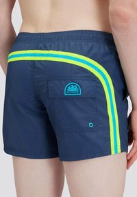 Pantaloni da nuoto navy con una striscia laterale a contrasto gialla e blu, vita elastica e una tasca sul retro con una toppa blu.