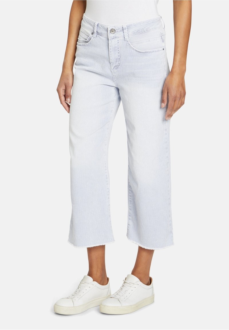 Jeans courts rayés bleu et blanc à taille haute, cinq poches, ourlet effiloché, associés à des baskets blanches.
