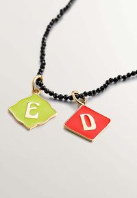 Collar de cuentas negras con dos colgantes de esmalte: un colgante en forma de diamante verde con una 'E' y un colgante cuadrado rojo con una 'D'.