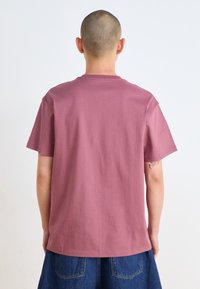 Short-sleeved t-shirt in dusty rose color, made of soft cotton. Classic crew neck with a relaxed fit and a smooth texture.