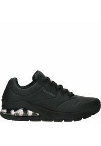 Scarpa sportiva nera con una superficie sintetica liscia, dettagli perforati, design con lacci e una suola trasparente con ammortizzazione ad aria.