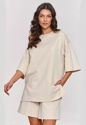 Beżowy, oversize t-shirt z krótkimi rękawami, okrągłym dekoltem i kieszeniami bocznymi; połączony z dopasowanymi beżowymi szortami, gładki materiał, luźny krój.