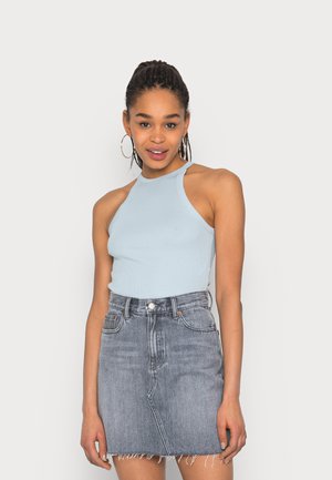 Top sem mangas de cor azul clara com nervuras, combinado com uma saia de ganga de cintura alta com bainha desfiada, lavagem média e bolsos frontais.