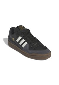 Svart och grå sneakers med tre vita ränder, tillverkade av mocka och läder, med texturerad yta, svarta snören och brun gummisula.