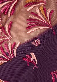 Tessuto ricamato con intricati motivi floreali in fili di rosa, viola e oro su una base di rete trasparente, con un bordo di colore viola scuro.
