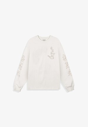Witte blouse met lange mouwen met de tekst "GRMY" en een dumpling-graphic op de borst, en gestileerde Aziatische karakters gedrukt op beide mouwen.