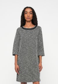 Rochie cu model houndstooth în alb și negru, cu o textură interesantă, mâneci trei sferturi și un decolteu rotund în negru.