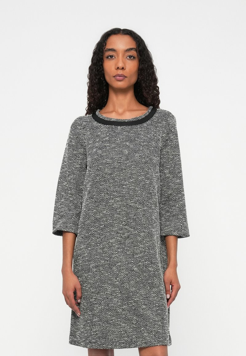 Rochie cu model houndstooth în alb și negru, cu o textură interesantă, mâneci trei sferturi și un decolteu rotund în negru.