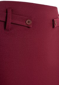 Gonna bordeaux con vestibilità su misura, realizzata in tessuto testurizzato, con vita piatta, doppi bottoni decorativi e passanti per la cintura.