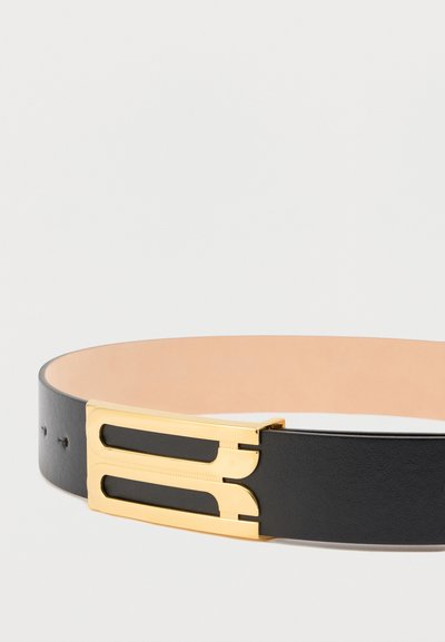 Μαύρη δερμάτινη ζώνη με χρυσή μεταλλική αγκράφα που διαθέτει δύο κομμένες ορθογώνιες σχηματισμούς. Το εσωτερικό επενδύεται με λείο μπεζ υλικό.