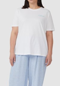 Witte katoenen t-shirt met korte mouwen en een ronde hals, voorzien van lichtblauwe geborduurde tekst. Gecombineerd met lichtblauwe gestreepte wijde broek.