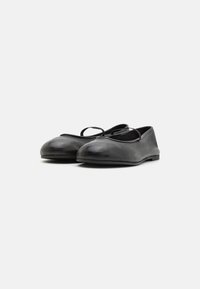 Ballerines en cuir noir avec un bout arrondi, dotées d'une fine sangle sur le coup de pied et d'une semelle plate. Texture lisse, design minimaliste.