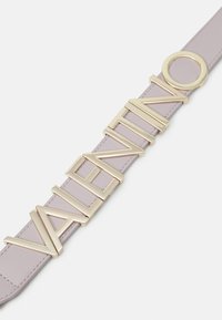 Jasnofioletowy skórzany pasek z dużym, złotym logo "Valentino" oraz okrągłym akcentem, podkreślający elegancki design.