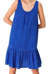 Robe sans manches bleue à pois blancs, décolleté arrondi, devant froncé et ourlet volanté. Fabriquée en tissu léger et texturé.