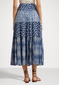 Maxikjol med ett flerlagersdesign i blått med blommor och paisleymönster; tillverkad av lättviktig tyg med en åtsittande midja.