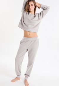 Lichtgrijs loungewear-set bestaande uit een cropped top met lange mouwen en taps toelopende joggerbroek met elastische tailleband, geribbelde textuur en geribbelde enkels.