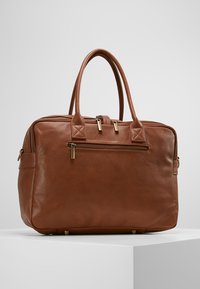 Borsa a mano in pelle marrone con doppi manici superiori, hardware dorato, tasca con zip sul davanti e forma rettangolare. Superficie testurizzata e piedi in ottone.