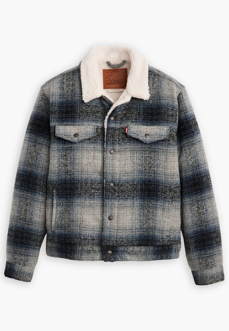 Veste en denim à carreaux dans des tons de bleu et de gris, avec un col en sherpa crème, deux poches poitrine et des fermetures à boutons métalliques.