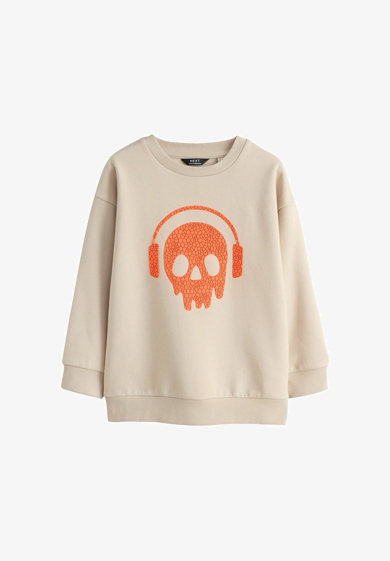 Sweatshirt beige avec un motif graphique de crâne orange craquelé portant un casque audio sur le devant, manches longues, poignets et ourlet côtelés.