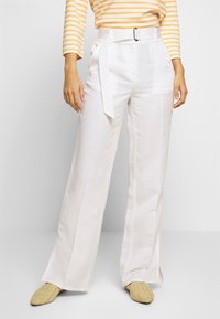 White wide-leg trousers made from lightweight fabric with a belted waist. Feature side pockets and a smooth texture.