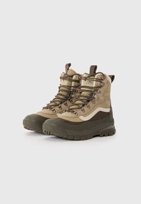 Kaki fotturer med et teksturert nylonoverdel, gummisåle, forsterket tå og metallhull. Har en mid-top design for støtte.