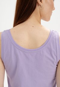 Lila ärmelloses Top mit weitem Ausschnitt und einer weichen Baumwolltextur. Nahtdetails sind an der Schulter und am Rücken sichtbar.