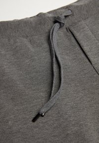 Grijze sweatpants met een textuurstof, een trekkoord met metalen punten en zijzakken, die comfort en functionaliteit benadrukken.