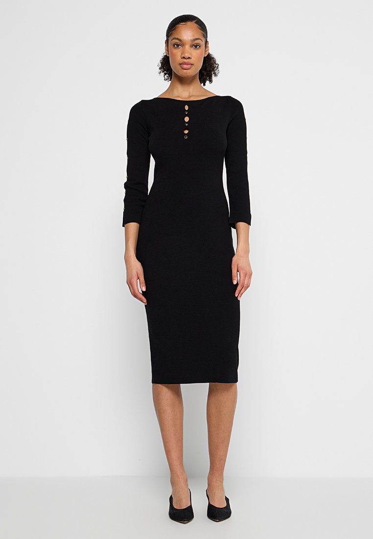 Zwarte jurk tot de knie, gemaakt van aansluitende stof, met lange mouwen, een boatneck en vier decoratieve knopen langs de voorkant.