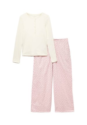 Top crema a maniche lunghe con bottoni abbinato a pantaloni rosa larghi con piccoli pois neri su sfondo bianco.