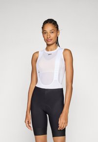White cycling bib with mesh design, printed logo, and black padded shorts. Features adjustable straps and close-fitting cut for comfort.