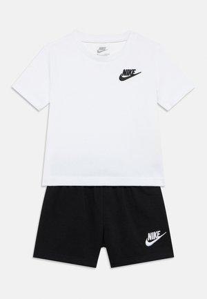 Két részes öltözet: fehér pamut póló fekete Nike logóval és fekete rövidnadrág, amelynek szegélyén hímzett Nike logó található.