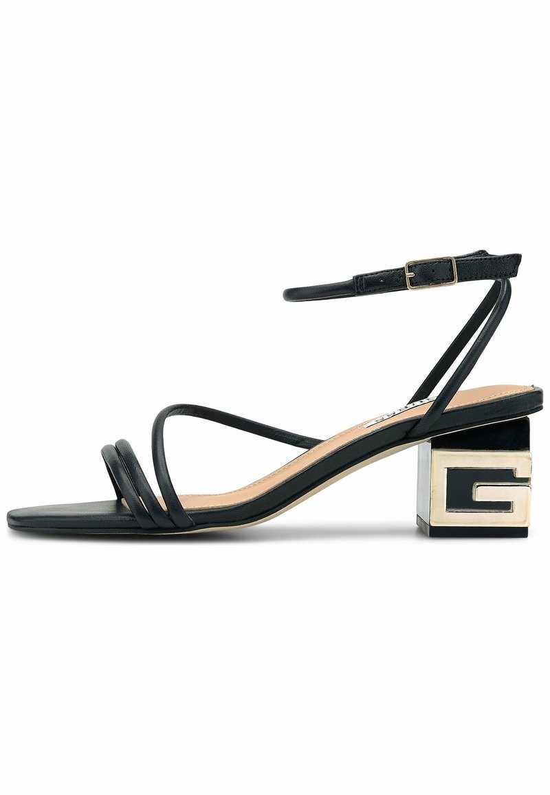 Sandale noire à brides avec bout carré, talon bloc bas avec détail métallique "G" et bride de cheville réglable avec boucle dorée.