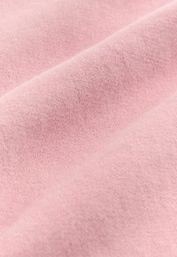Blød rosa bomuldsstof med en glat tekstur, der viser subtile variationer i nuancer og fine strikkedetaljer, arrangeret i blide folder.
