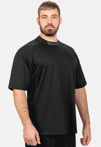 Zwarte T-shirt met korte mouwen, gemaakt van zachte stof, met een ronde halslijn en kenmerkende borduurwerk op de borst.