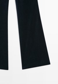 Pantalon noir à jambes larges avec un ourlet net présenté sur un fond clair.