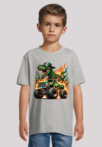 Grijze katoenen t-shirt met een cartoon dinosaur die een zonnebril draagt, een monstertruck bestuurt, met vlammen en camouflage-details.